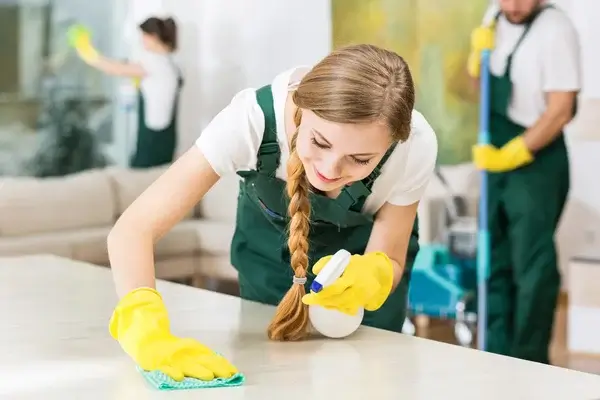 Syndrome de Diogène : qu'est-ce c'est ? Femme nettoyant une table passant un coup d'éponge avec un sourire
