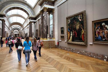 Galerie du musée du Louvre avec tableaux et visiteurs.