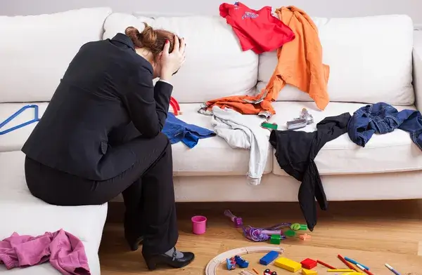 canapé en désordre et femme qui se prend la tête